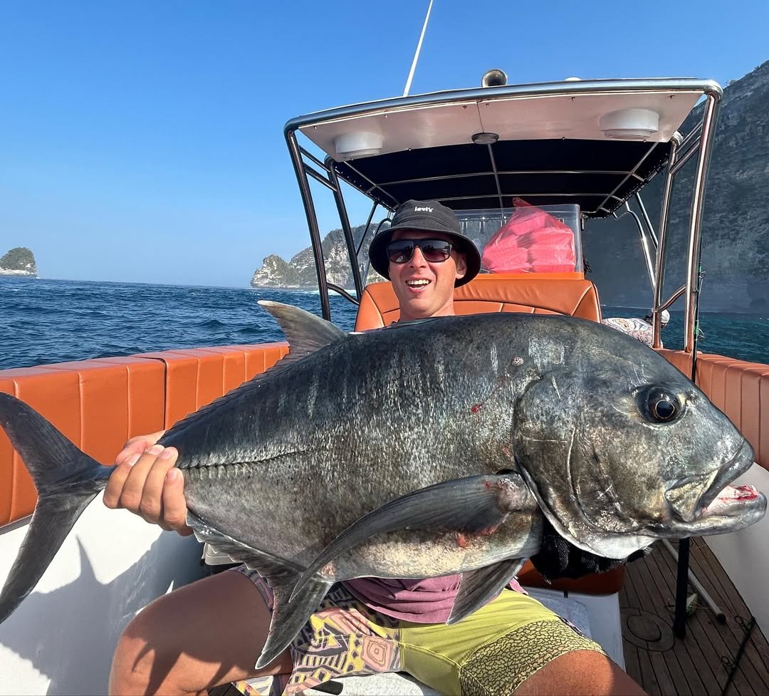 Happy tourist holding black GT during Bali fishing charter