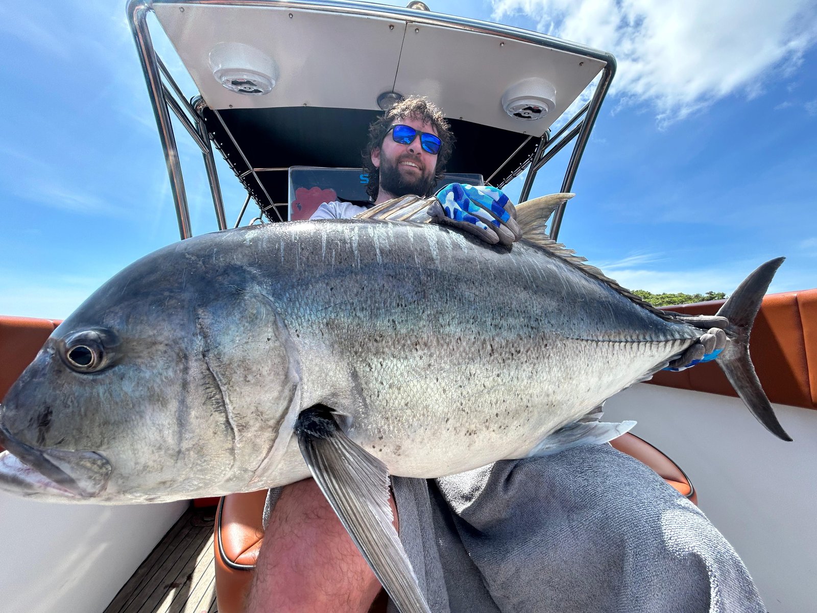 Happy tourist holding black GT during Bali fishing charter